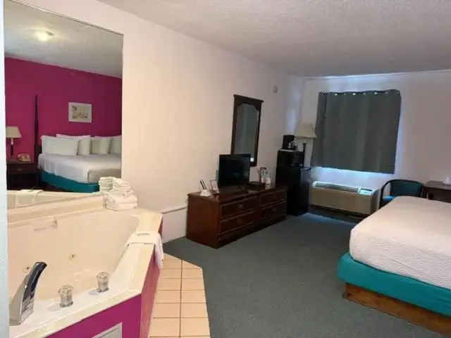 a hotel room with a bathroom with a bed and a tub at UP NORTH HOTEL formerly Voyager Inn in Saint Ignace
