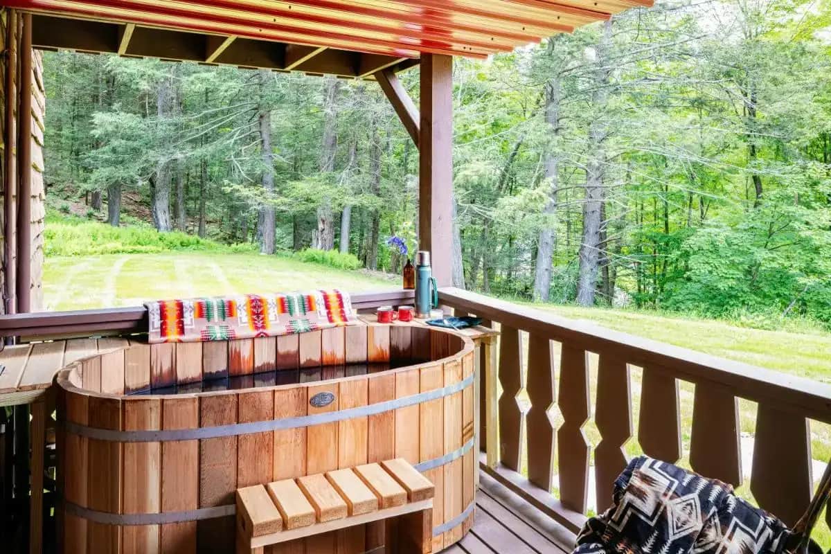 a wooden deck with a hot tub on a porch at Urban Cowboy Lodge in Big Indian