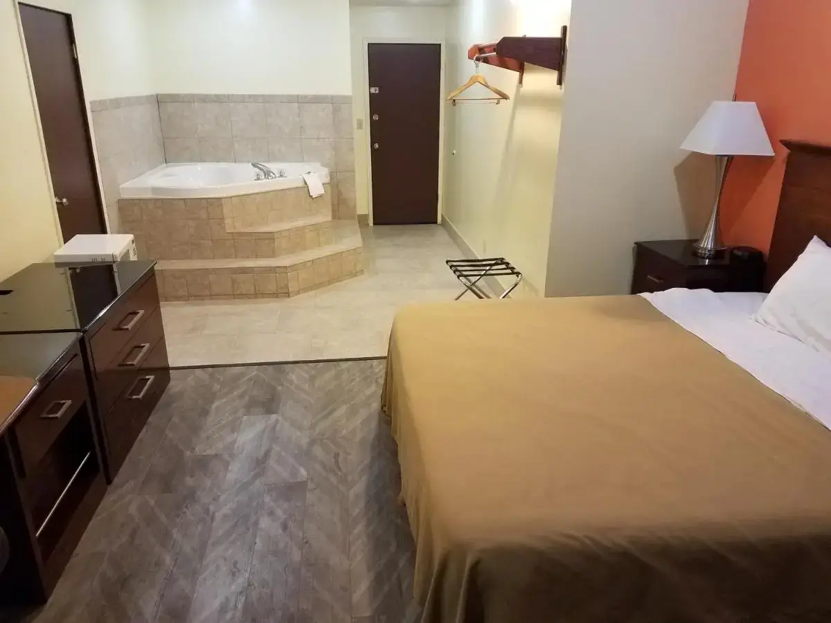 a hotel room with a bed and a bath tub at Western Inn South in Kearney