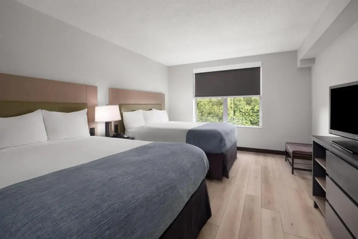 a hotel room with two beds and a flat screen tv at Wingate by Wyndham Matthews - Charlotte in Matthews