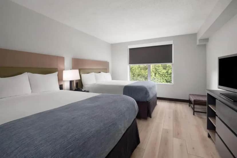 a hotel room with two beds and a flat screen tv at Wingate by Wyndham Matthews - Charlotte in Matthews