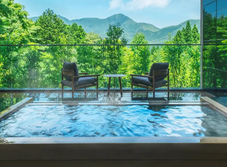 A private outdoor hot tub on a hotel terrace looking out over forested hills