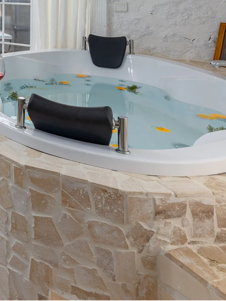 A round jetted whirlpool tub beside the bed in a hotel suite